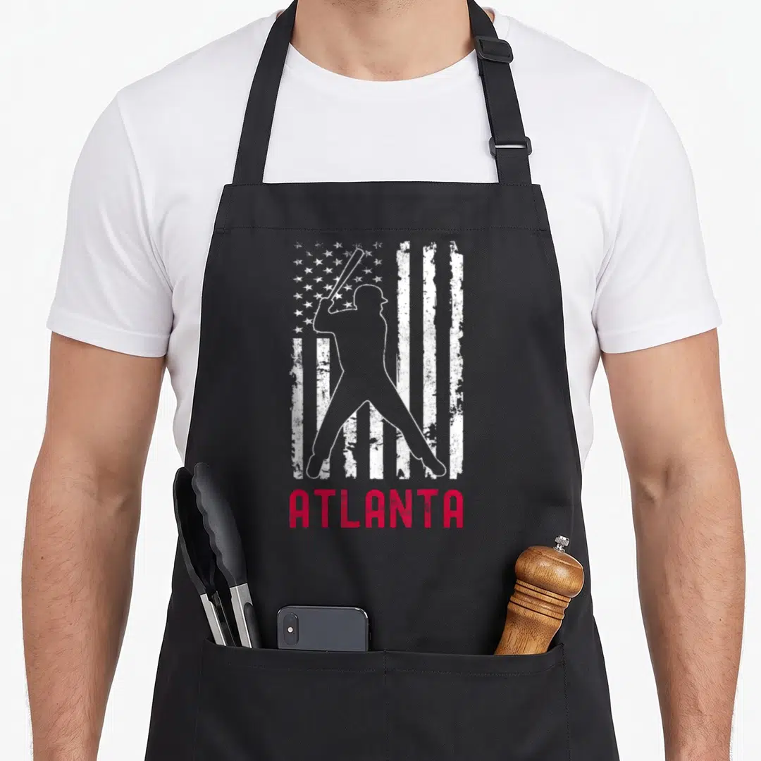 Atlanta american flag apron - White baseball batter silhouette over distressed flag with red ATLANTA text below — shown on a black cotton canvas apron against a white background