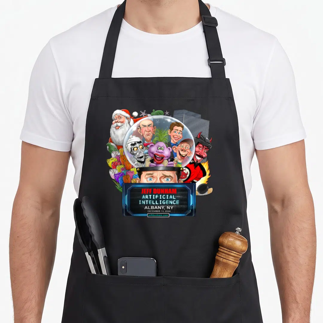Jeff fan gear apron - Jeff Dunham characters in snow globe with eyes below and blue text box reading Albany NY Dec 13 — shown on a black cotton canvas apron against a white background