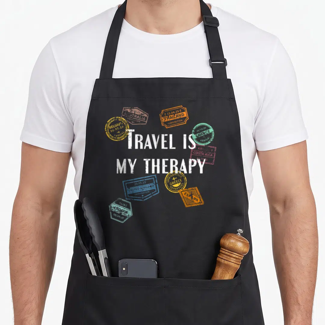 Distressed travel aprons - White distressed text surrounded by colorful passport stamps from Belgium and Greece — shown on a black cotton canvas apron against a white background
