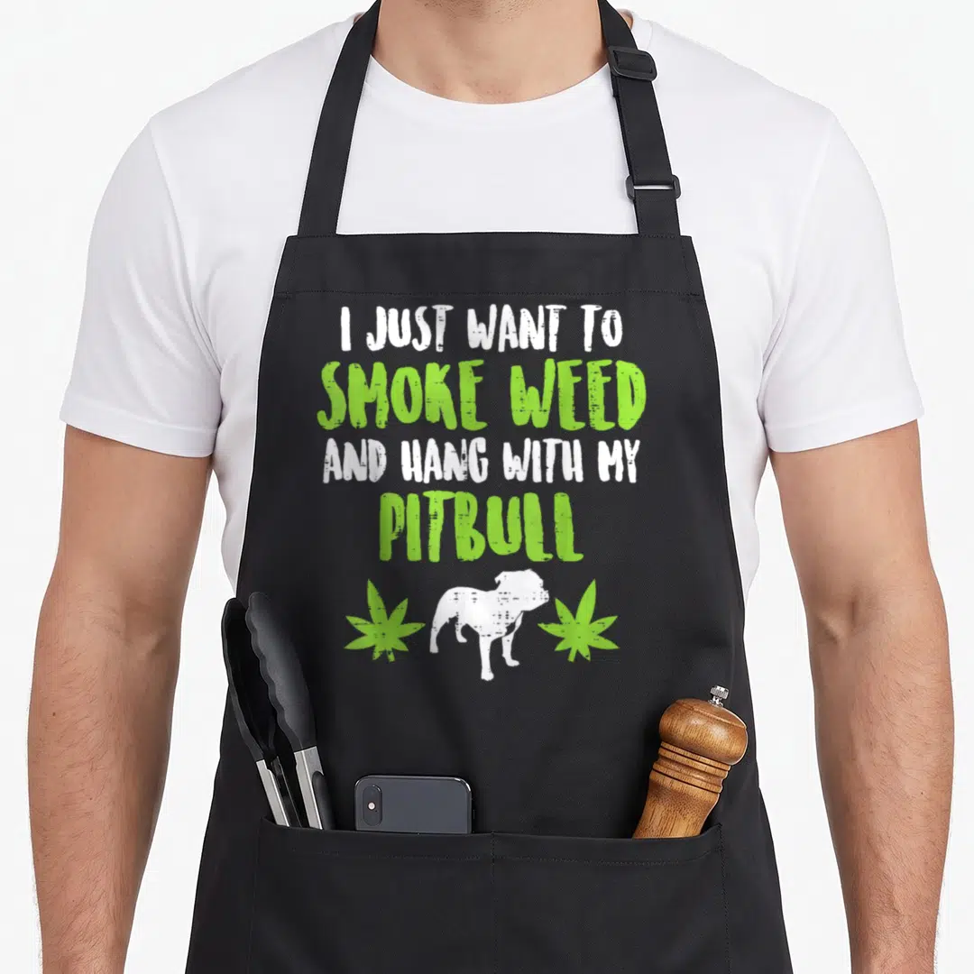 Smoke dog apron - I just want to smoke weed and hang with my pitbull text with dog and leaves — shown on a black cotton canvas apron against a white background