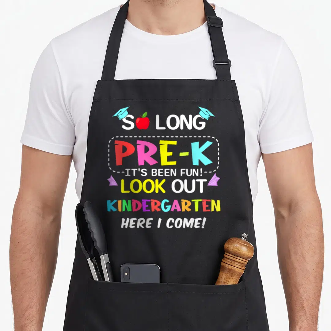 Pre come and get it apron - Stacked colorful Pre-K graduation text with apple, caps, and planes — shown on a black cotton canvas apron against a white background