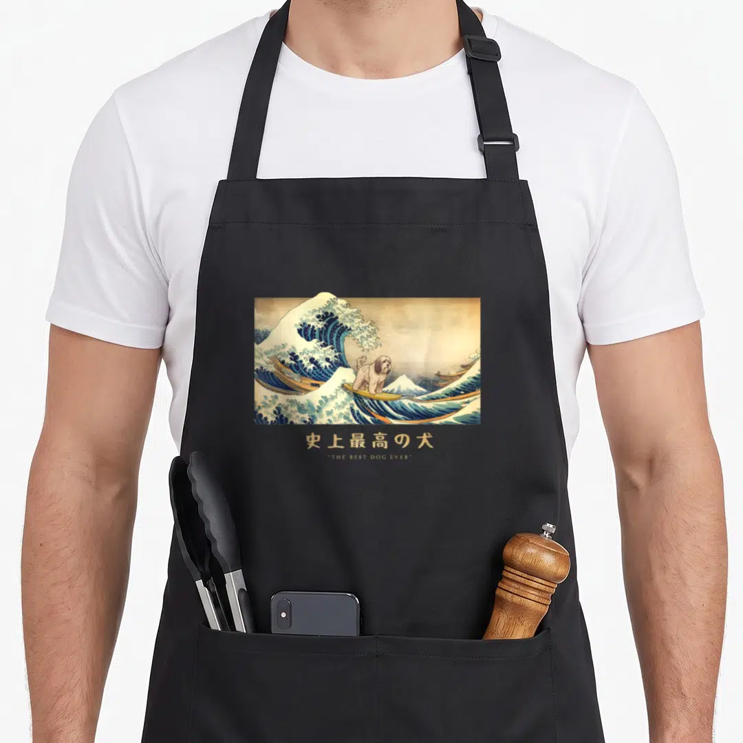 Surfing tibetan apron - Dog surfing a blue wave with THE BEST DOG EVER text below — shown on a black cotton canvas apron against a white background