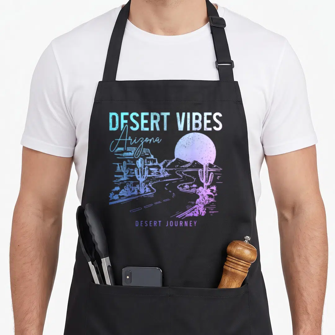 Arizona modern apron - Retro desert landscape print with cacti, sun, and road in blue purple pink gradient — shown on a black cotton canvas apron against a white background