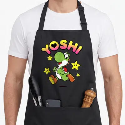Star holiday apron - Green cartoon dinosaur running under arched YOSHI text with four yellow stars scattered around — shown on a black cotton canvas apron against a white background