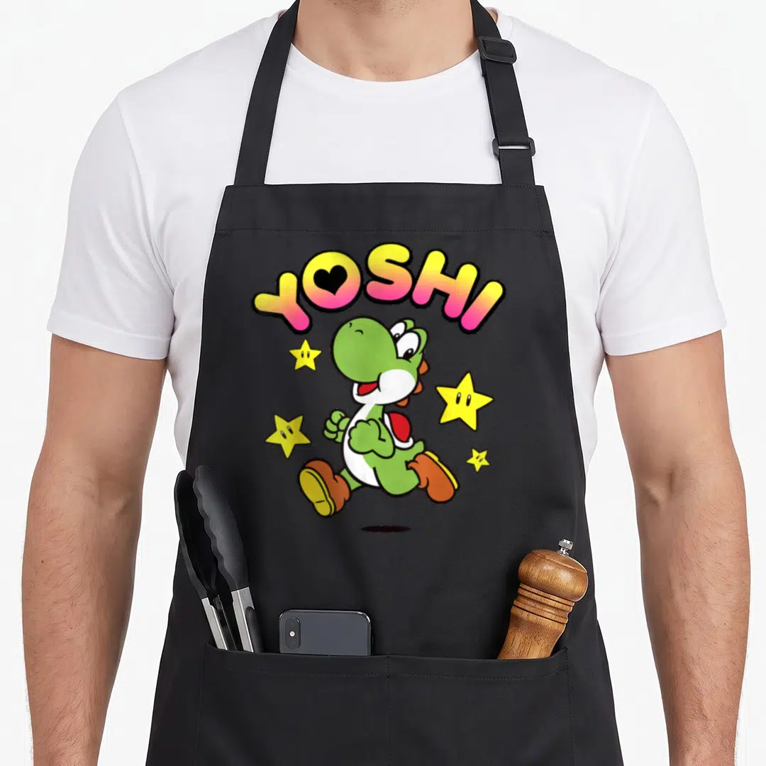 Star holiday apron - Green cartoon dinosaur running under arched YOSHI text with four yellow stars scattered around — shown on a black cotton canvas apron against a white background
