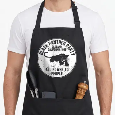 Funny distressed apron for grilling - Circular distressed logo with grey panther and Black Panther Party Oakland 1966 — shown on a black cotton canvas apron against a white background