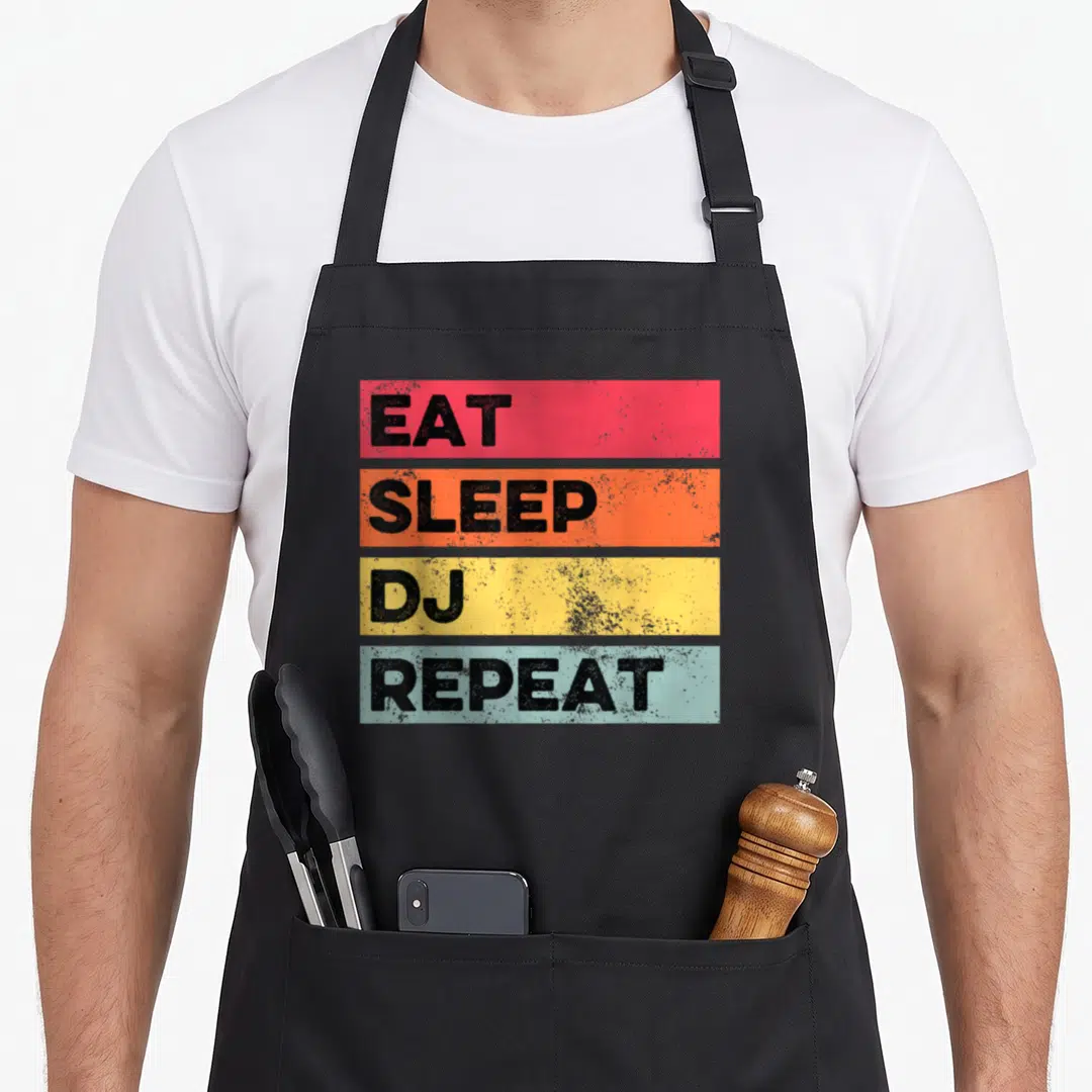 Eat djing apron - EAT SLEEP DJ REPEAT text in red orange yellow blue distressed bars — shown on a black cotton canvas apron against a white background