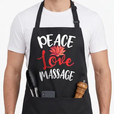 Peace massage therapist apron - PEACE Love MASSAGE text with red lotus flower graphic — shown on a black cotton canvas apron against a white background