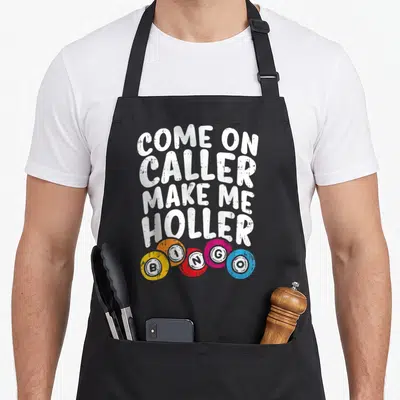 Come bingo apron - White text Come On Caller Make Me Holler above five colorful BINGO chips on black fabric — shown on a black cotton canvas apron against a white background