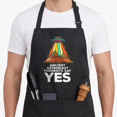 Ancient meme apron - Cartoon UFO beam on three pyramids with text Ancient Astronaut Theorists Say Yes in orange yellow — shown on a black cotton canvas apron against a white background