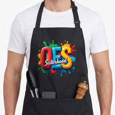 Watercolor oes apron - Large 3D OES letters with Sisterhood script over red blue yellow green paint splashes — shown on a black cotton canvas apron against a white background