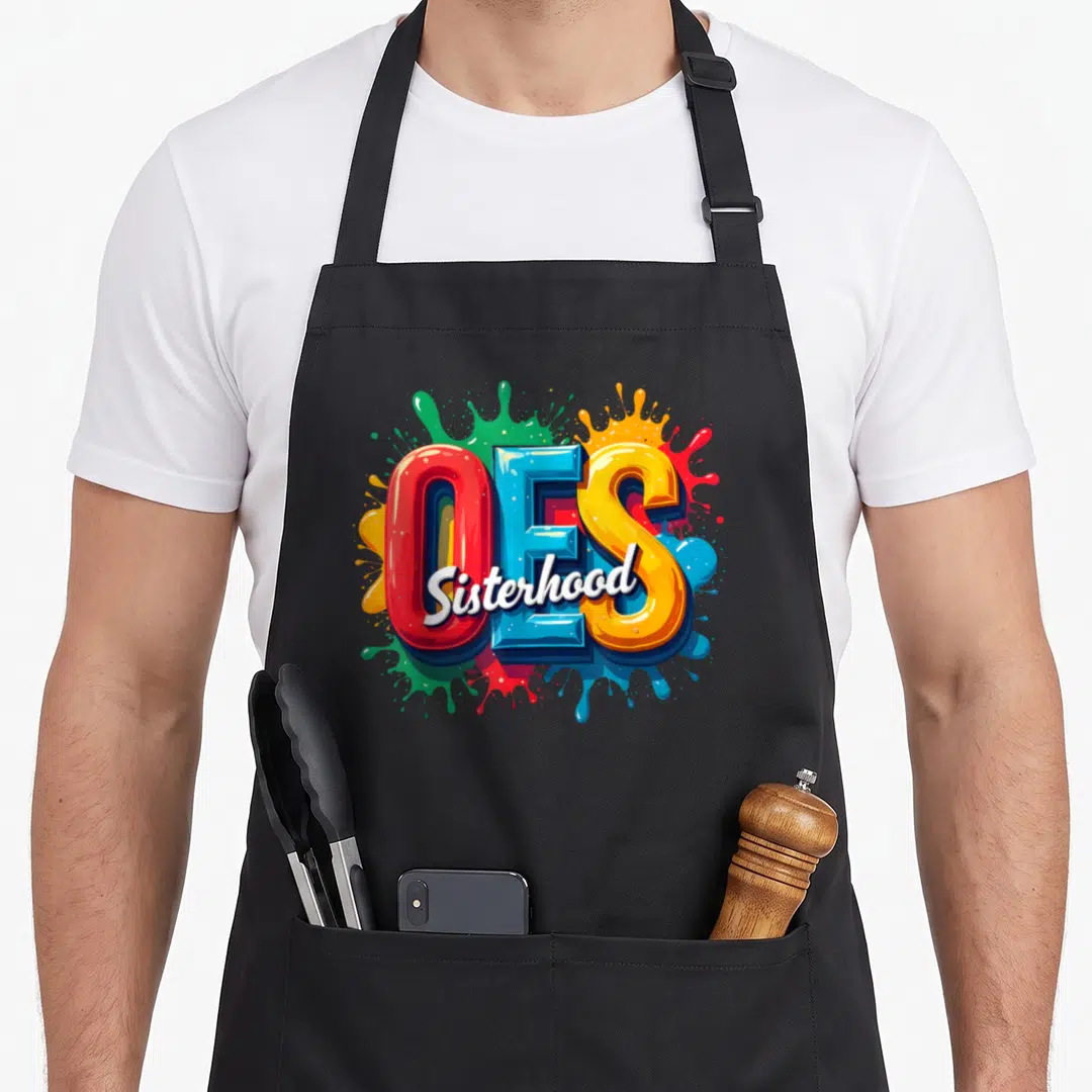 Watercolor oes apron - Large 3D OES letters with Sisterhood script over red blue yellow green paint splashes — shown on a black cotton canvas apron against a white background
