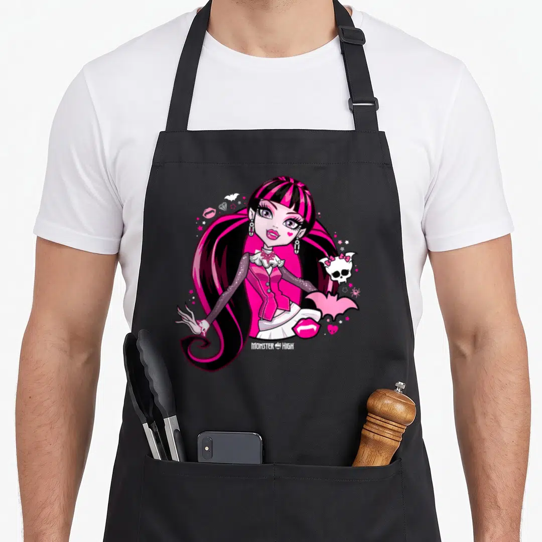 Draculaura monster high apron - Pink and black cartoon vampire girl surrounded by bats, lips, and skull icons — shown on a black cotton canvas apron against a white background