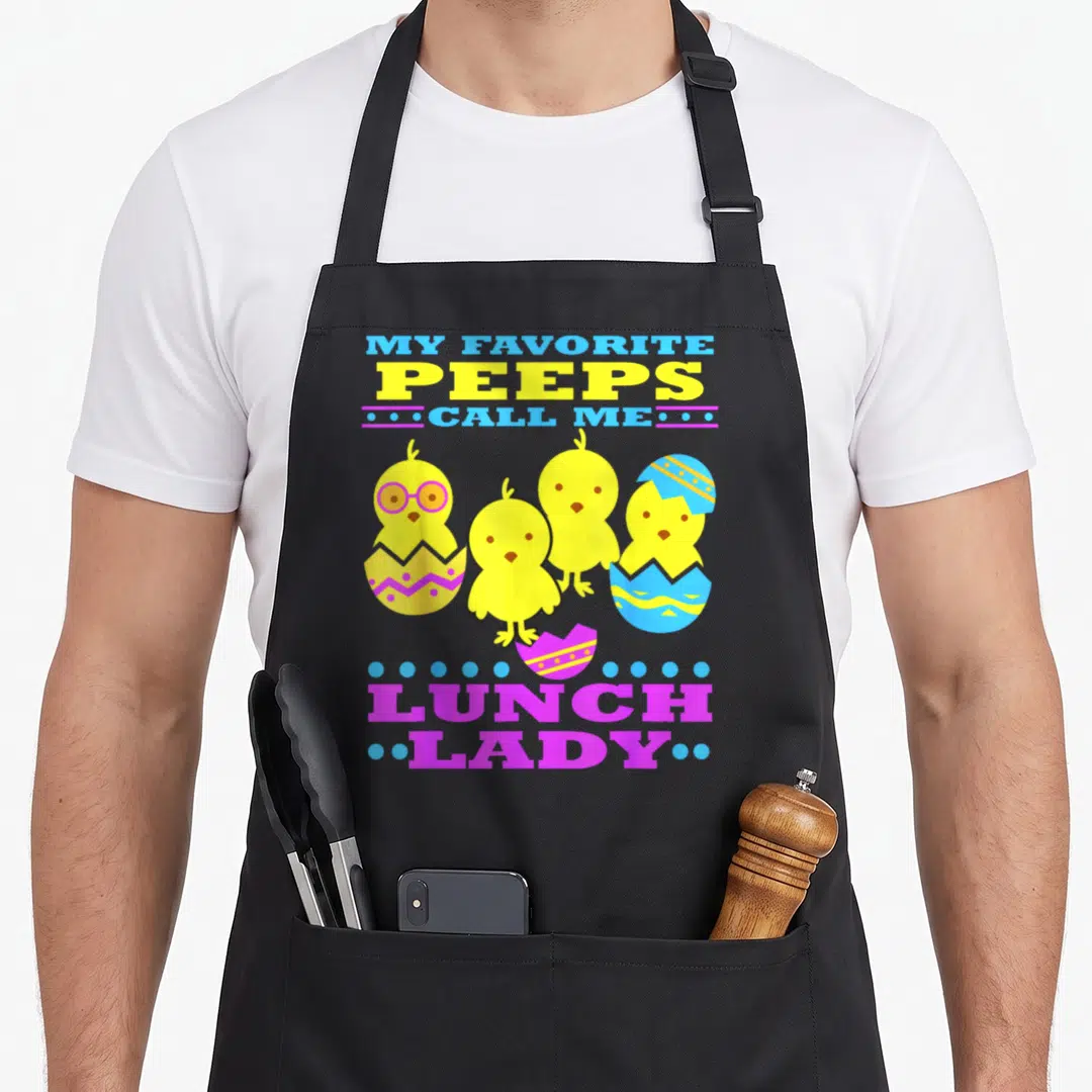 Easter cafeteria aprons - Four yellow chicks with eggshells and My Favorite Peeps Call Me Lunch Lady text in blue — shown on a black cotton canvas apron against a white background