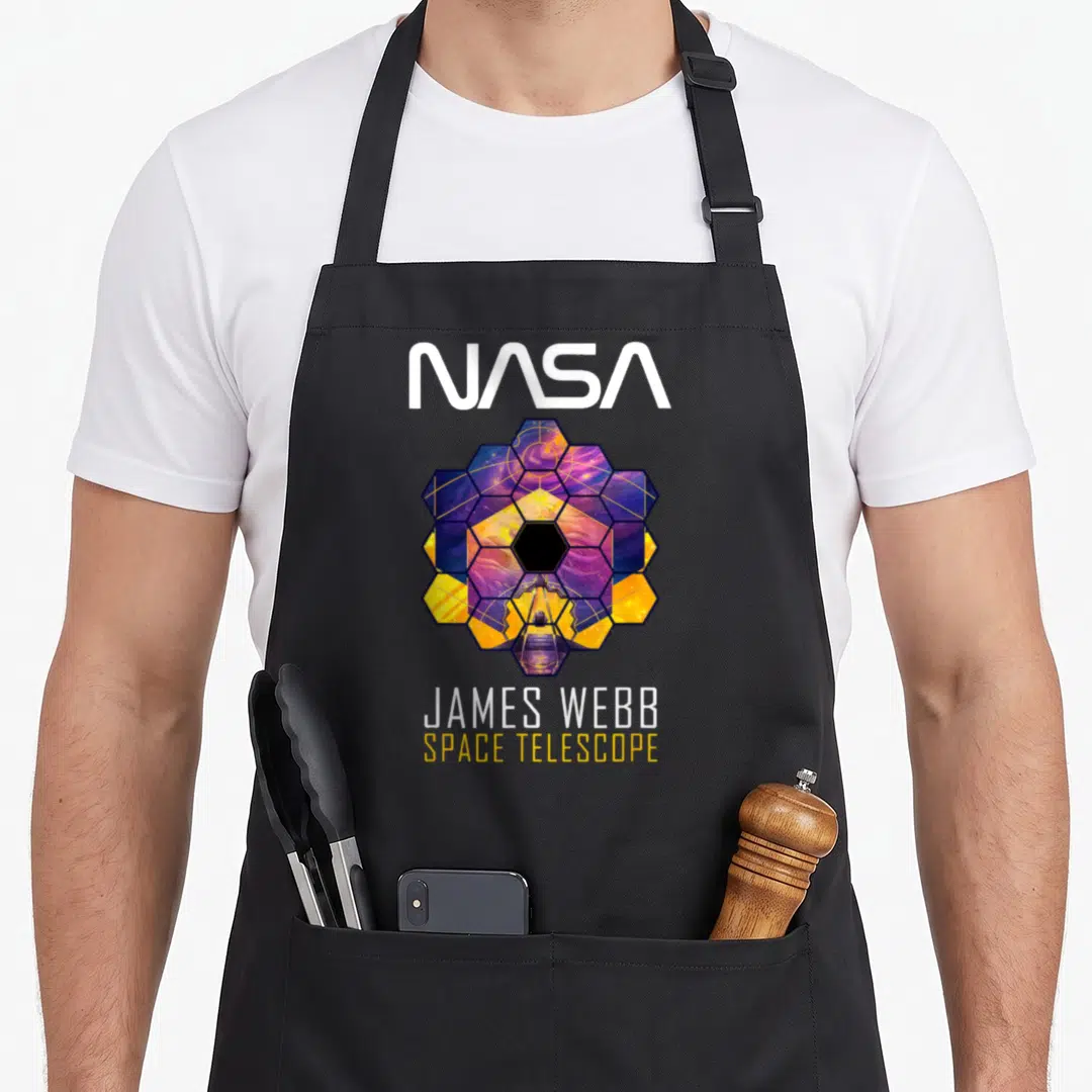 Jame telescope apron - NASA logo above hexagonal mirror array with JAMES WEBB SPACE TELESCOPE text below — shown on a black cotton canvas apron against a white background