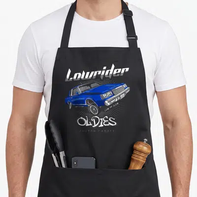 Oldy mexican apron - Blue lowrider car graphic with Lowrider OLDIES CUSTOM GARAGE text on grey sunburst — shown on a black cotton canvas apron against a white background