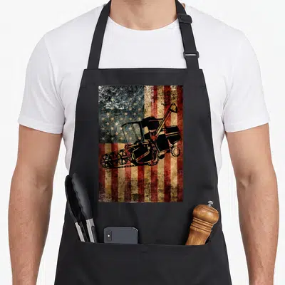 Distressed farm apron - Black combine harvester silhouette on a distressed red, white, blue, and black American flag — shown on a black cotton canvas apron against a white background