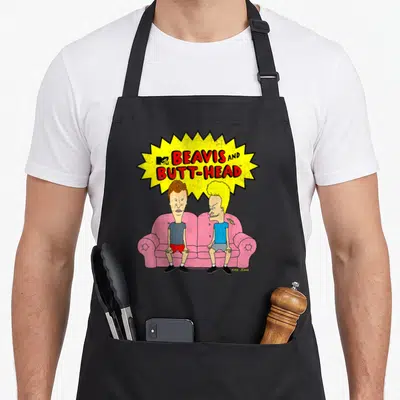 Butt couch apron - Beavis and Butt-Head on pink sofa under yellow burst with red text and MTV logo — shown on a black cotton canvas apron against a white background
