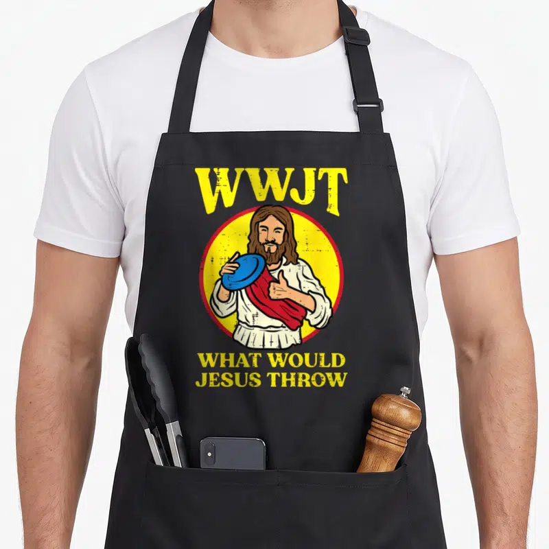 Wwjt golf apron - Distressed graphic of Jesus holding a blue disc with WWJT text in yellow — shown on a black cotton canvas apron against a white background