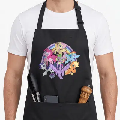 Friendship magic apron - Six ponies clustered before rainbow arch with MY LITTLE PONY logo in purple pink blue yellow — shown on a black cotton canvas apron against a white background