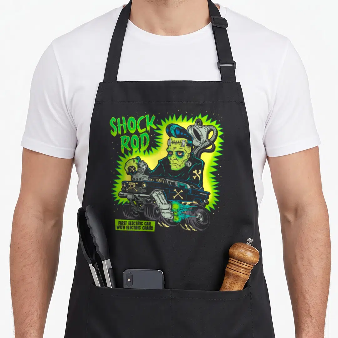 Frankenstein horror apron - Green monster behind grey gasser with SHOCK ROD text and jagged yellow glow — shown on a black cotton canvas apron against a white background