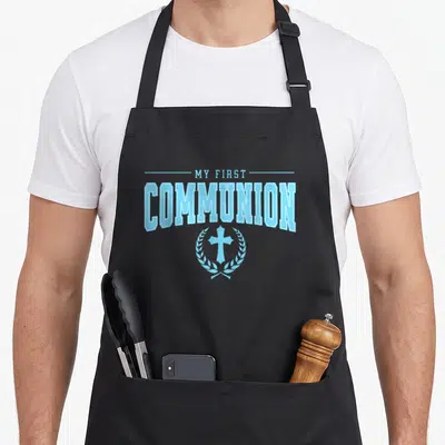 Religious communion aprons - Stacked MY FIRST COMMUNION text above a blue cross inside a wreath — shown on a black cotton canvas apron against a white background