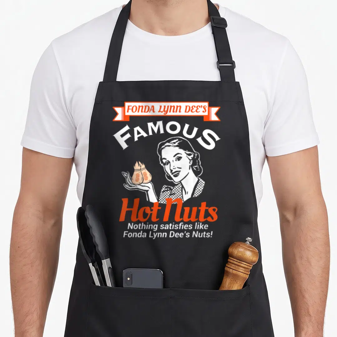 Fonda crazy vulture man apron - Retro graphic of woman holding burning nuts with stacked text Fonda Lynn Dee's Famous — shown on a black cotton canvas apron against a white background