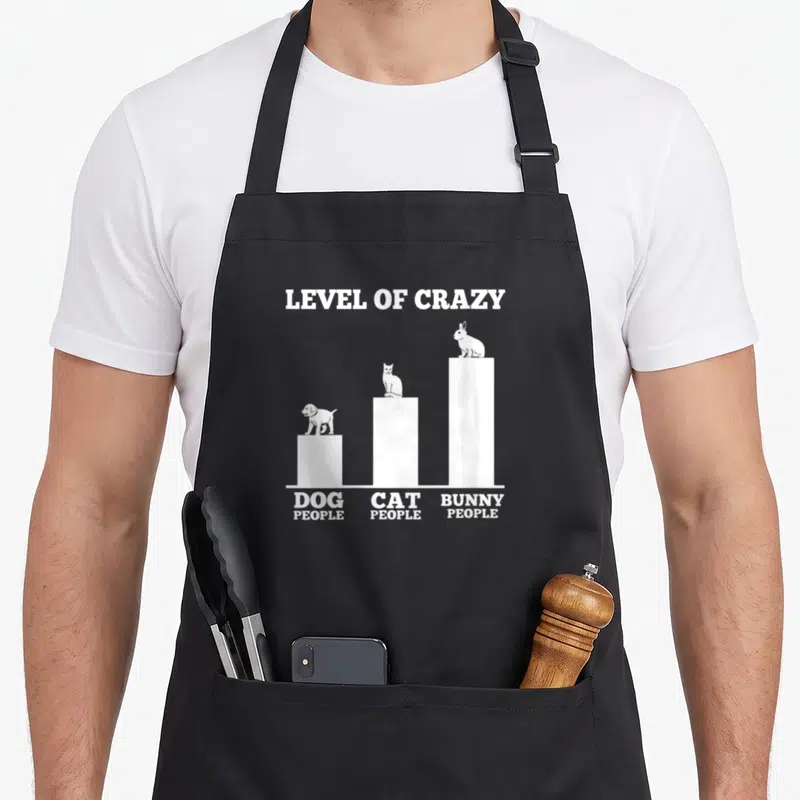 Outfit rabbit owner bunny apron - White bar chart with dog cat and bunny silhouettes labeled levels of crazy — shown on a black cotton canvas apron against a white background