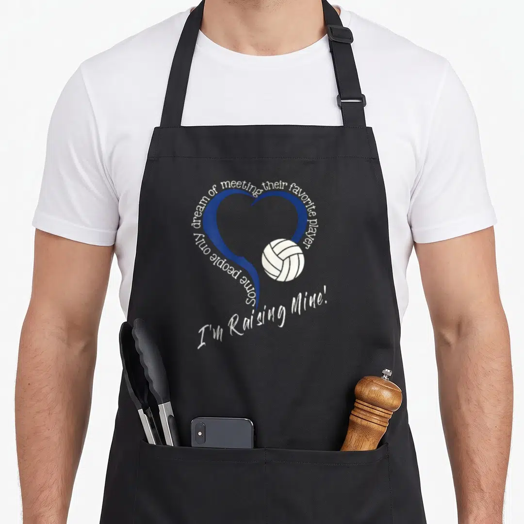 Raising volleyball apron - Blue heart with white volleyball and curved text reading Some people only dream of meeting — shown on a black cotton canvas apron against a white background
