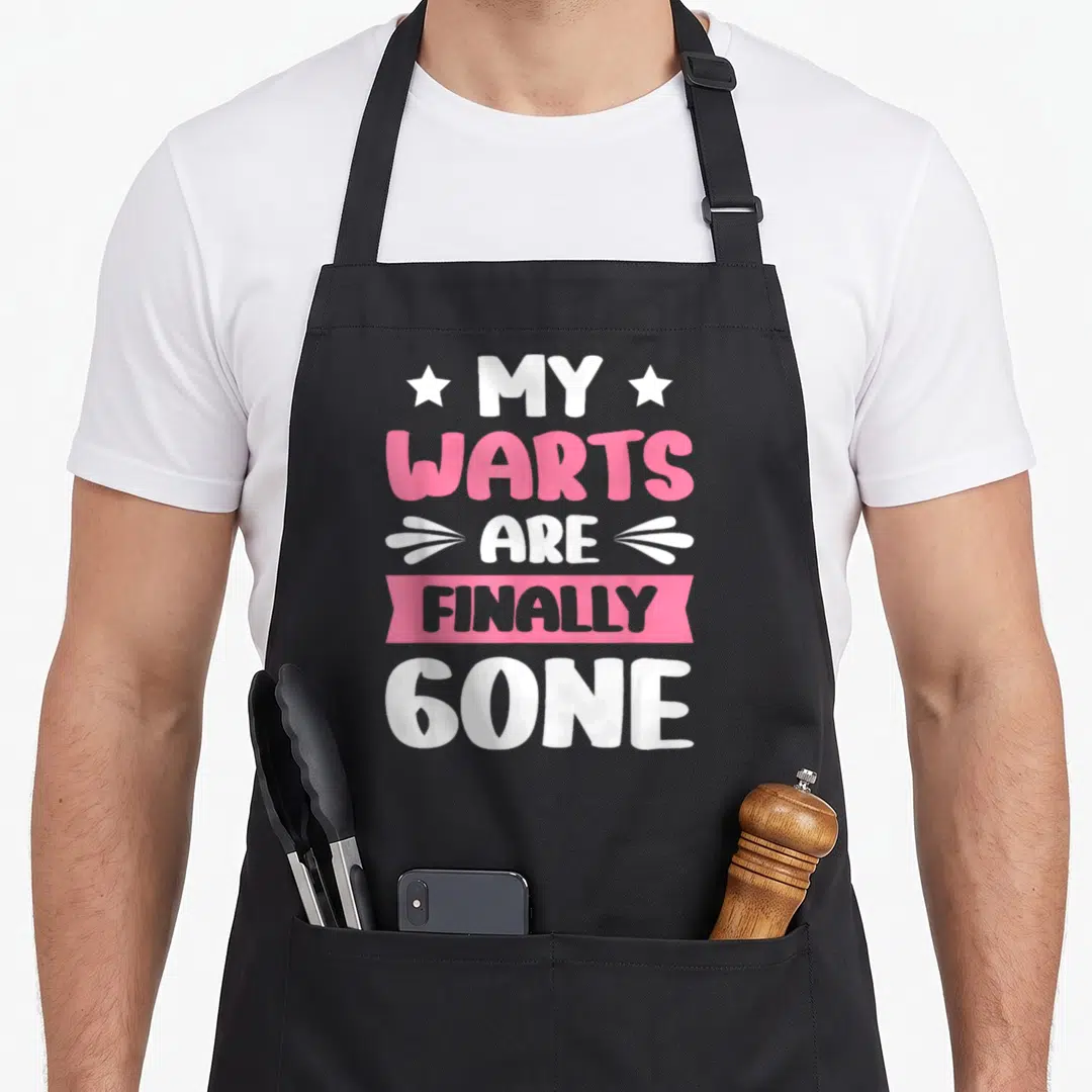 Finally funny wart apron - White and pink stacked text reading MY WARTS ARE FINALLY GONE with stars and banner graphics — shown on a black cotton canvas apron against a white background