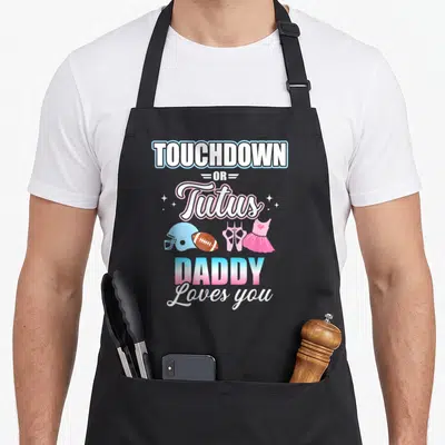 Touchdown daddy apron - Stacked text TOUCHDOWN OR Tutus DADDY Loves you with football helmet, ball, ballet shoes — shown on a black cotton canvas apron against a white background