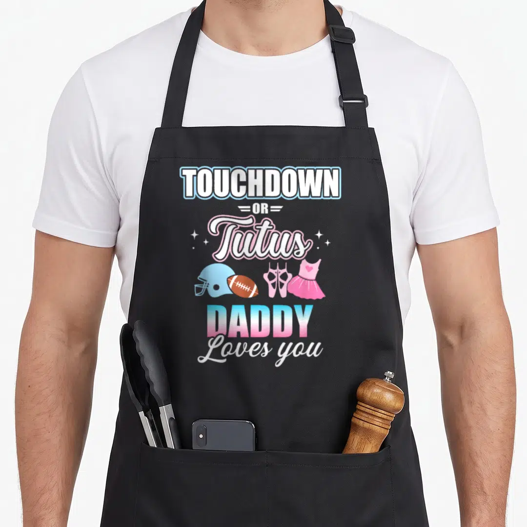 Touchdown daddy apron - Stacked text TOUCHDOWN OR Tutus DADDY Loves you with football helmet, ball, ballet shoes — shown on a black cotton canvas apron against a white background