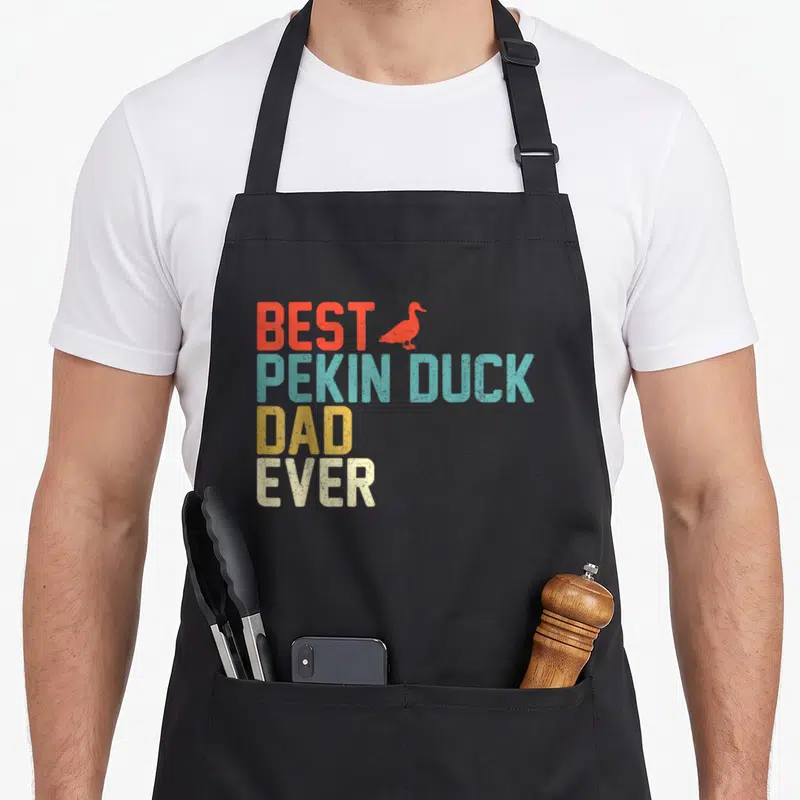 Pekin cotton duck apron - Retro stacked text Best Pekin Duck Dad Ever with red duck silhouette in red blue yellow beige — shown on a black cotton canvas apron against a white background