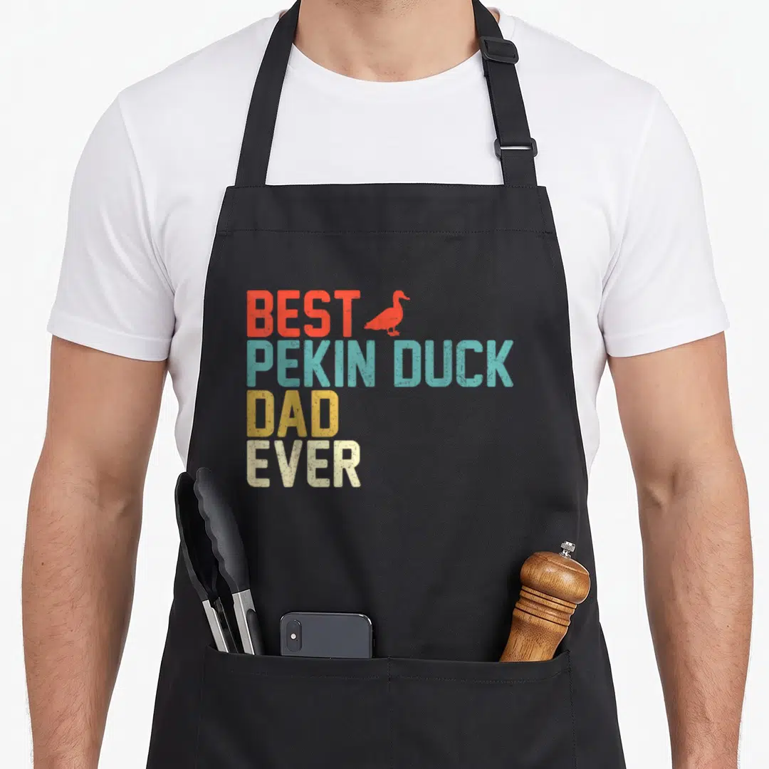 Pekin cotton duck apron - Retro stacked text Best Pekin Duck Dad Ever with red duck silhouette in red blue yellow beige — shown on a black cotton canvas apron against a white background