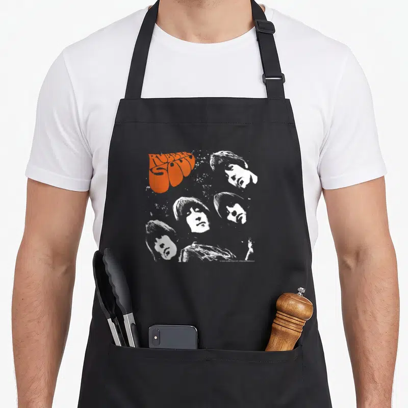 Sole rubber apron - Orange RUBBER SOUL text and four white distressed portraits of men — shown on a black cotton canvas apron against a white background