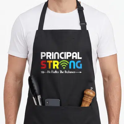 Strong future principal apron - PRINCIPAL STRONG text with wifi symbol and arrow containing No Matter The Distance — shown on a black cotton canvas apron against a white background