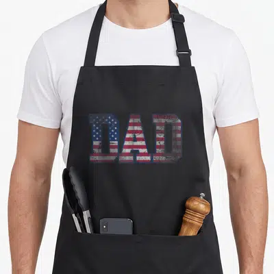Father patriotic aprons - Distressed DAD text filled with red white and blue stars and stripes pattern — shown on a black cotton canvas apron against a white background