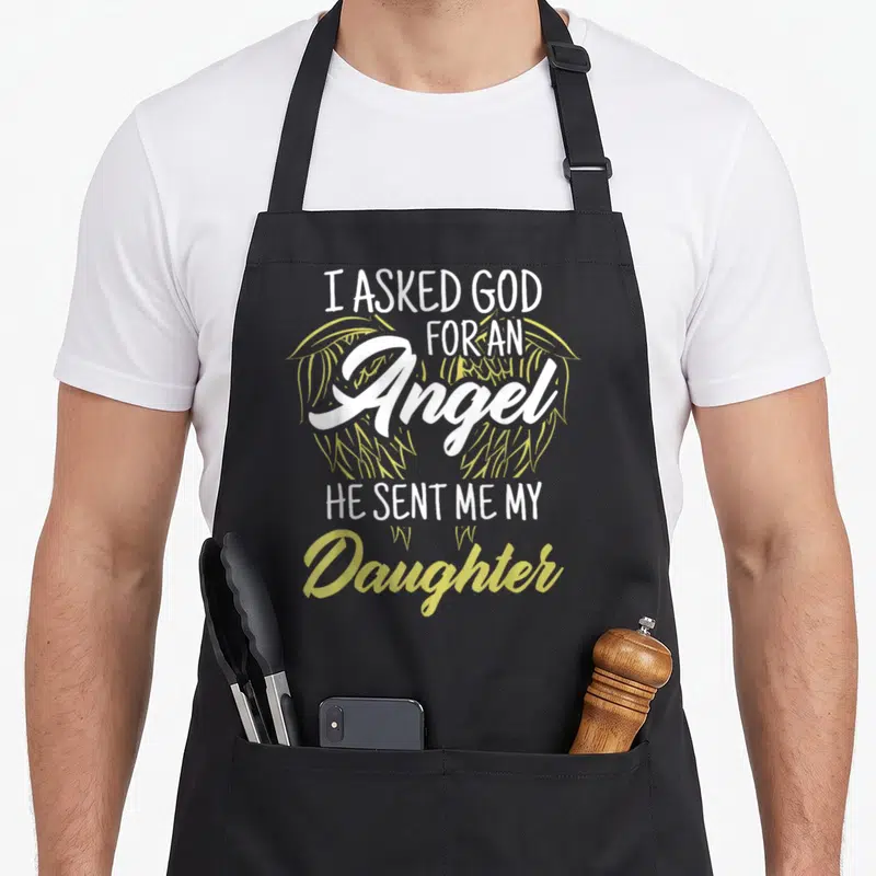 Asked god angel mom daughter apron - Stacked white and yellow-green text reading I Asked God For An Angel He Sent Me My — shown on a black cotton canvas apron against a white background