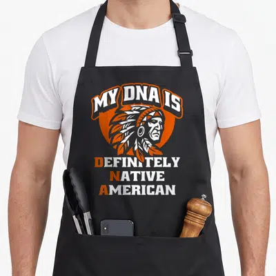 Dna native american aprons - Cartoon Native American man in orange circle with My DNA Is Definitely Native American text — shown on a black cotton canvas apron against a white background