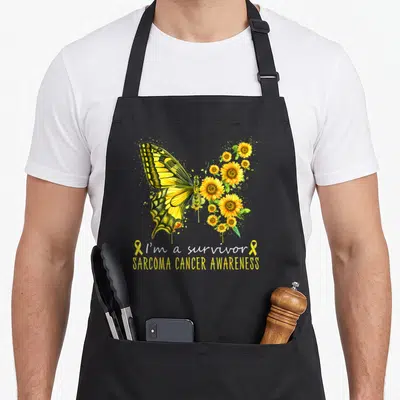 Survivor sarcoma awareness apron - Yellow butterfly with sunflower wings and I'm a survivor text on black apron — shown on a black cotton canvas apron against a white background