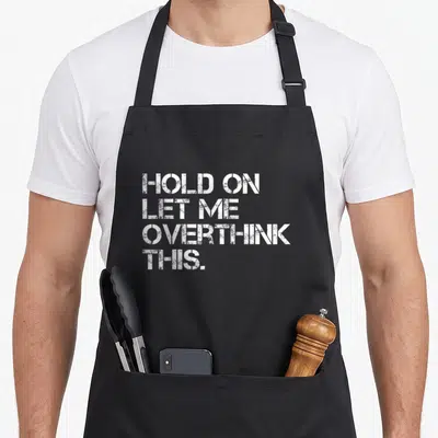 Hold sarcastic apron - White stacked typography reading Hold On Let Me Overthink This on grey background — shown on a black cotton canvas apron against a white background