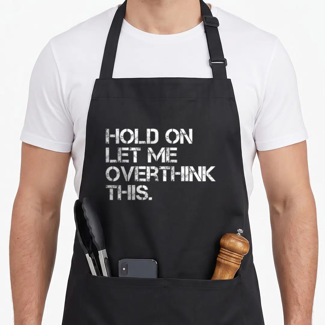 Hold sarcastic apron - White stacked typography reading Hold On Let Me Overthink This on grey background — shown on a black cotton canvas apron against a white background