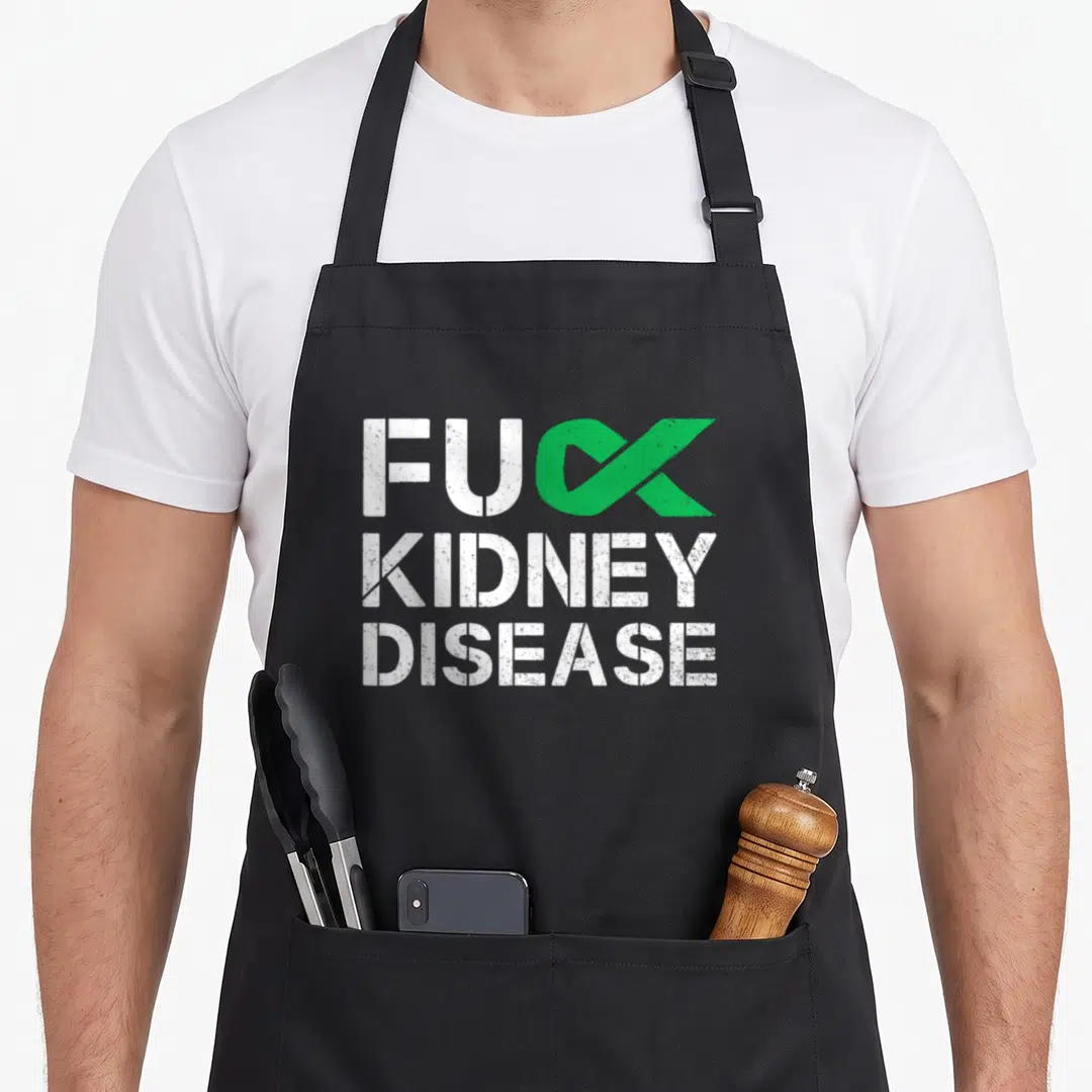 Disease ribbon apron - FUC KIDNEY DISEASE text with green ribbon replacing the K in distressed white font — shown on a black cotton canvas apron against a white background