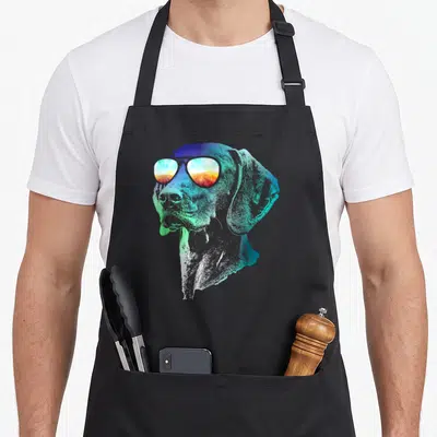Groovy dog apron - Dog head profile wearing sunglasses with blue green and orange gradient art — shown on a black cotton canvas apron against a white background