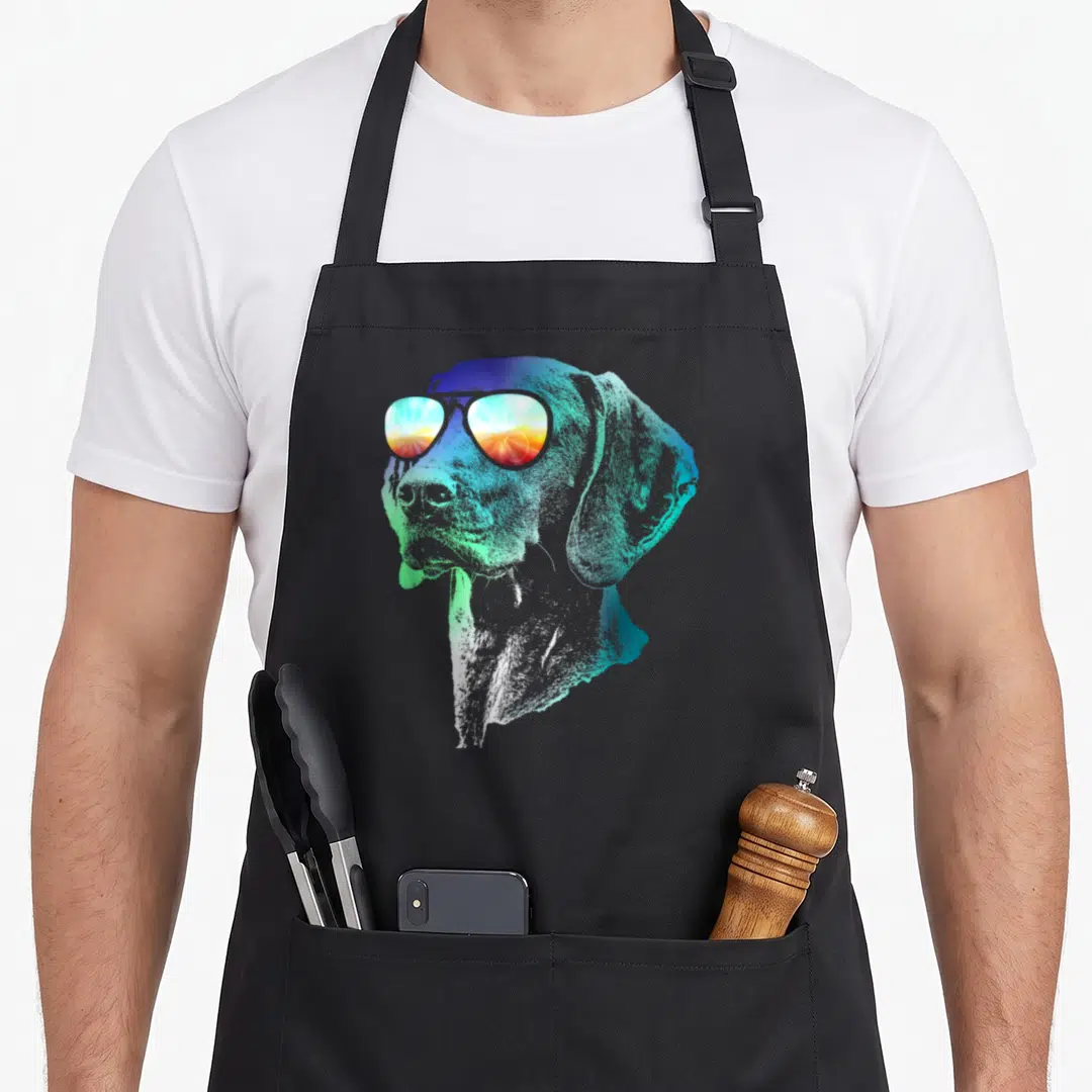 Groovy dog apron - Dog head profile wearing sunglasses with blue green and orange gradient art — shown on a black cotton canvas apron against a white background