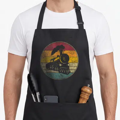Train engineer apron - Grey steam locomotive silhouette over red orange yellow and green retro stripes — shown on a black cotton canvas apron against a white background