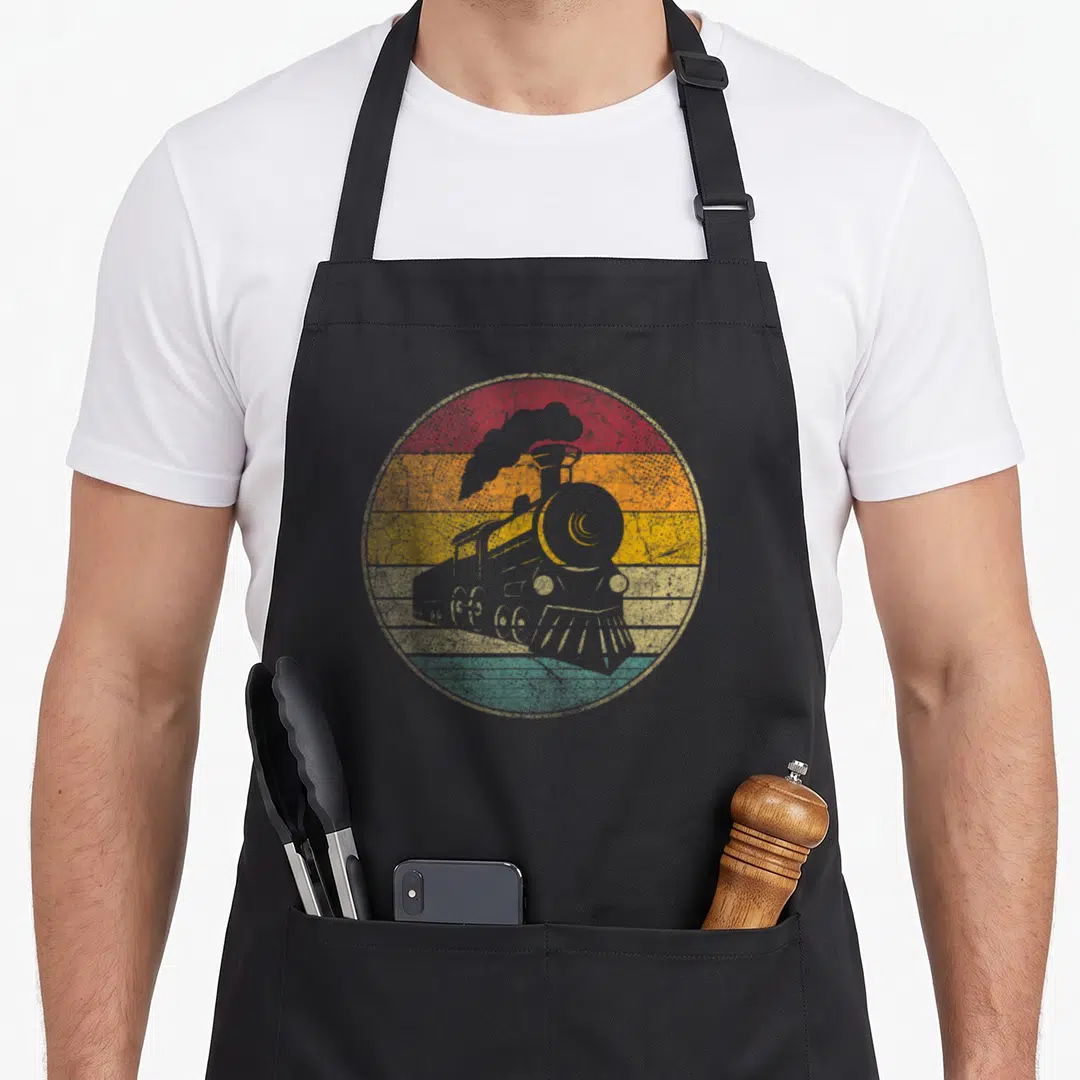 Train engineer apron - Grey steam locomotive silhouette over red orange yellow and green retro stripes — shown on a black cotton canvas apron against a white background