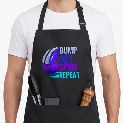 Bump girls volleyball apron - Stylized brush stroke ball next to stacked text BUMP SET SPIKE REPEAT in purple and blue — shown on a black cotton canvas apron against a white background