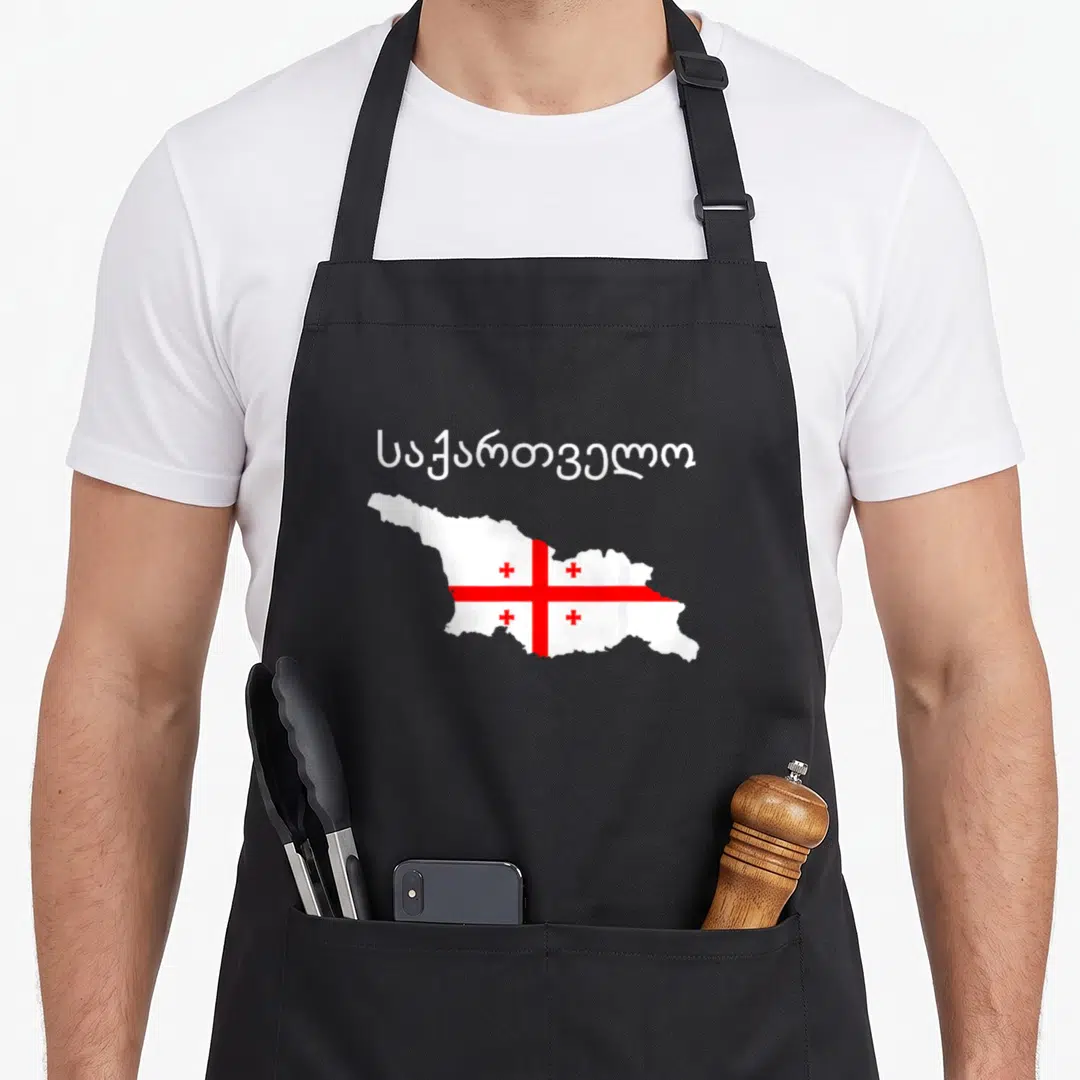 Republic georgian apron - Sakartvelo text above a map of Georgia filled with the white and red flag pattern — shown on a black cotton canvas apron against a white background
