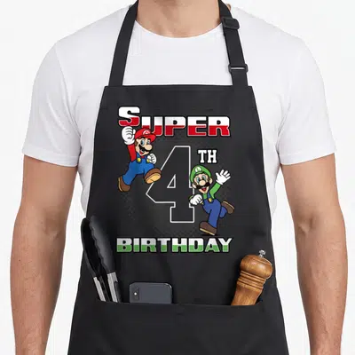 Birthday holiday apron - Mario and Luigi cartoon characters flanking large 4th Birthday number in red and green — shown on a black cotton canvas apron against a white background